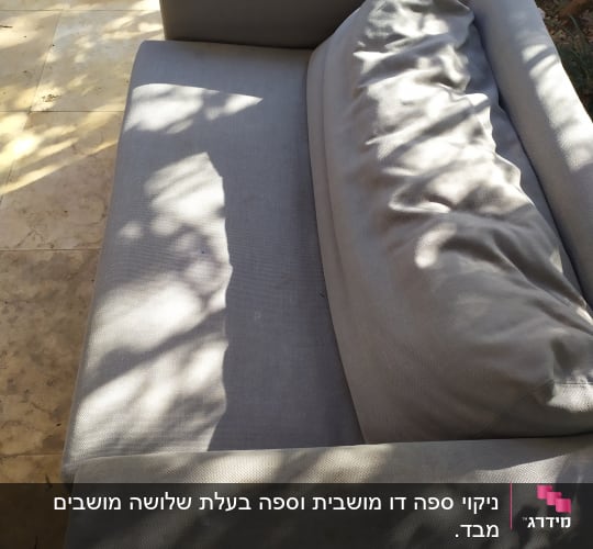 ספה אפורה עם כרית על משטח אבן